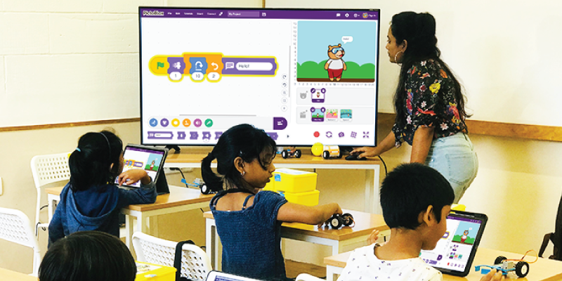 Primary school teacher teaching early-age students in a classroom to create and animate stories with coding using Junior Blocks