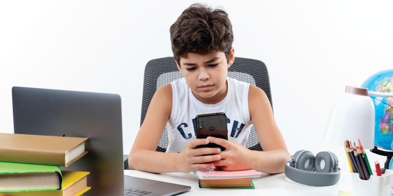 A young kid distracted by a smartphone instead of studying questions the role of technology in education