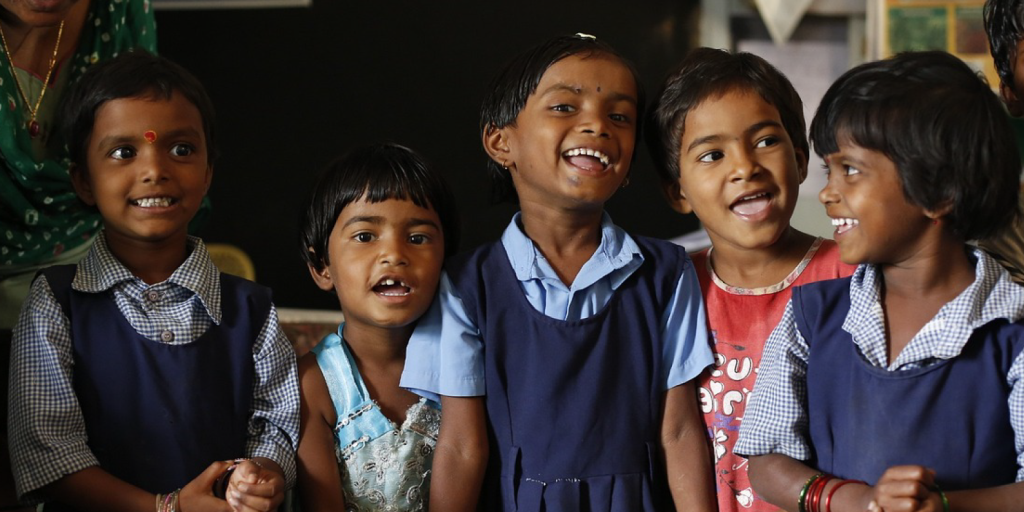 Group of Indian children smiling in school uniforms, representing the impact of Sarva Shiksha Abhiyan